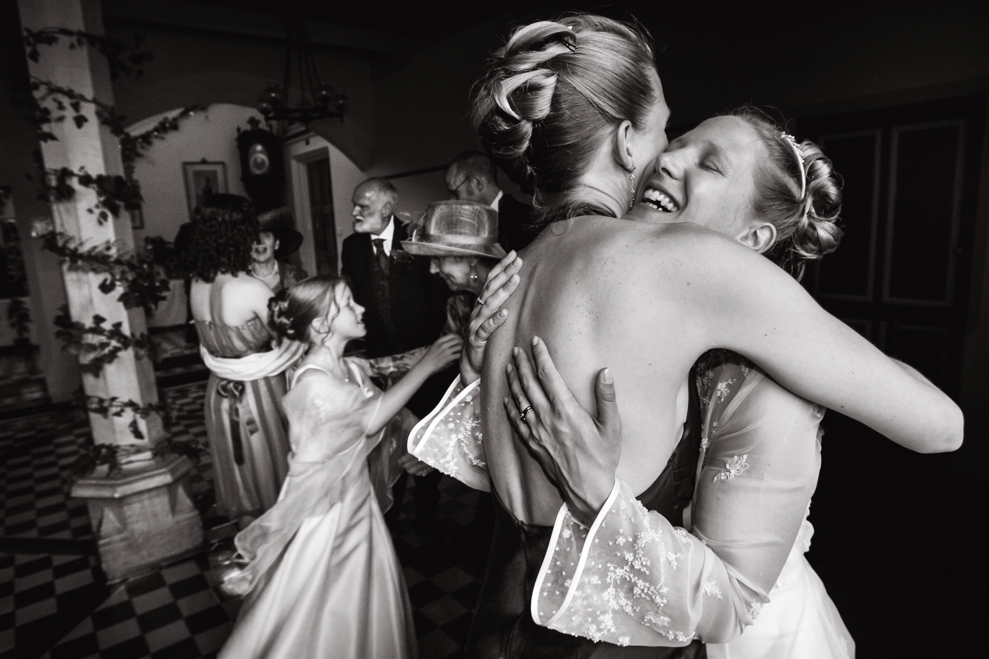 Black and white photograph of a bride hugging her sister after her wedding ceremony taken by wedding photographer Richard Eaton.