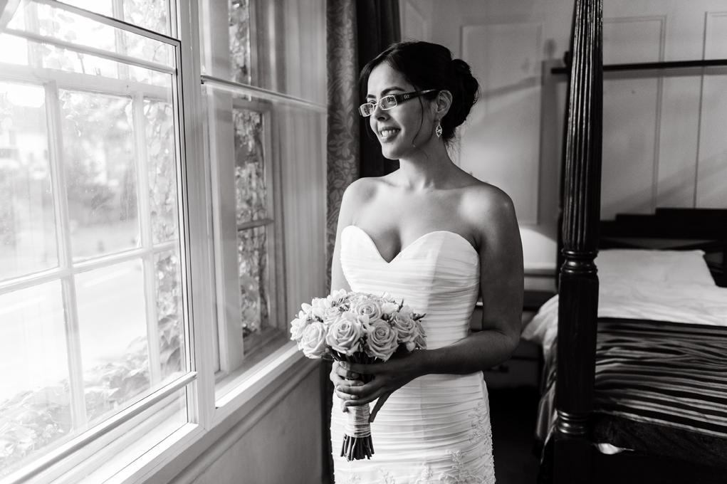Bride posing by window on her wedding day taken by Surrey based wedding photographer Richard Eaton. 