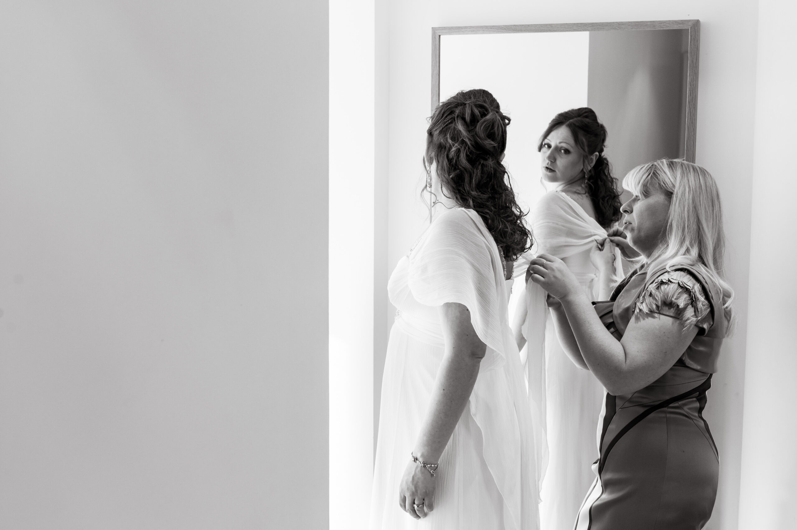 Bride getting ready in front of a mirror on her wedding day taken by Surrey based wedding photographer Richard Eaton. 