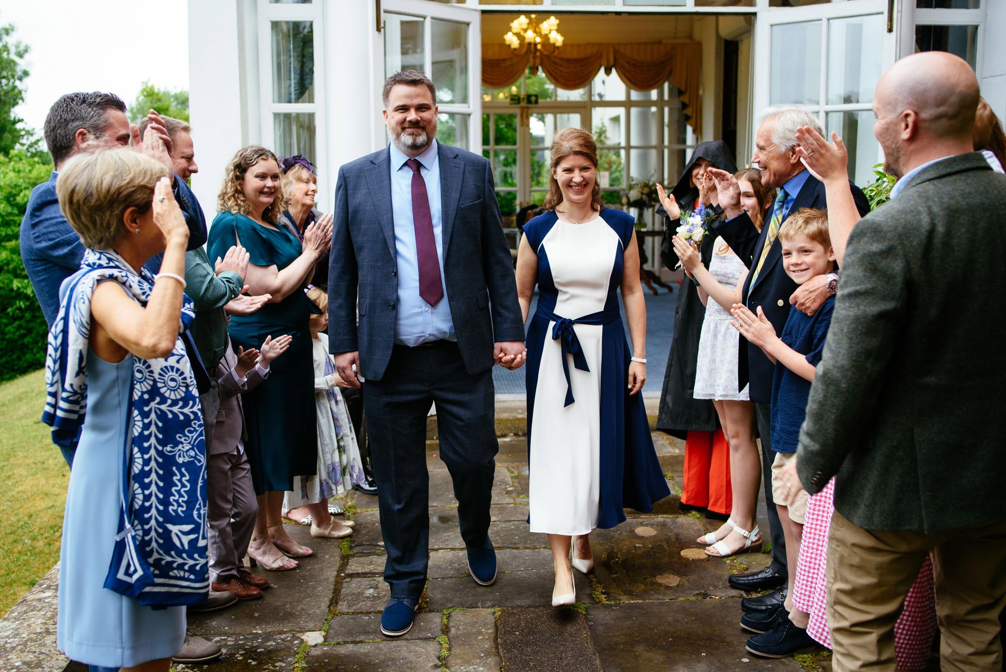 A newly married couple walk through a line of their family and friends after their wedding ceremony taken by wedding photographer Richard Eaton.